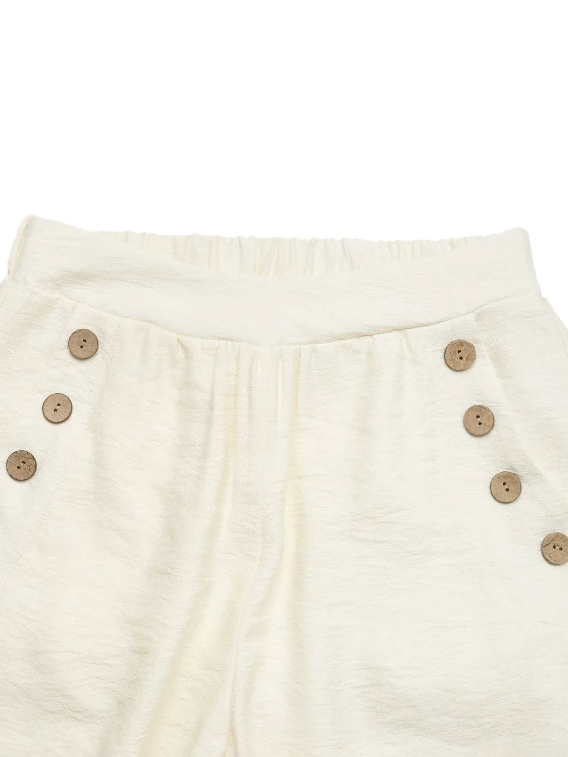 Close-up of cream-colored pants with button details on a white background