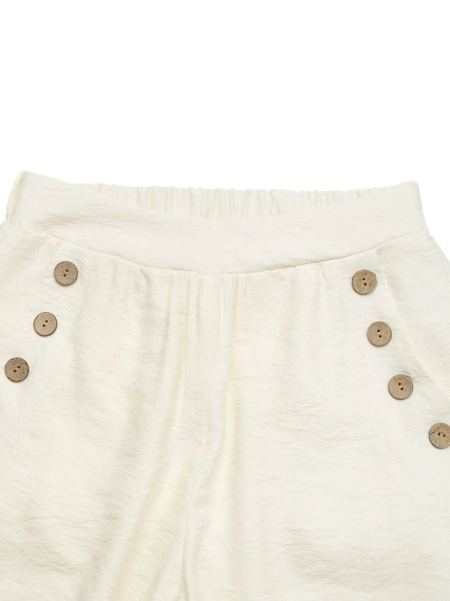 Close-up of cream-colored pants with button details on a white background