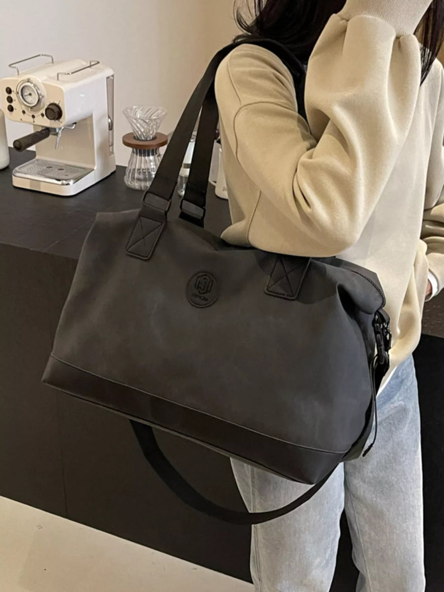 Person holding a black bag in a kitchen setting with a sewing machine and other items.