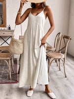 Woman in a white dress holding a straw bag in a room with wooden furniture.