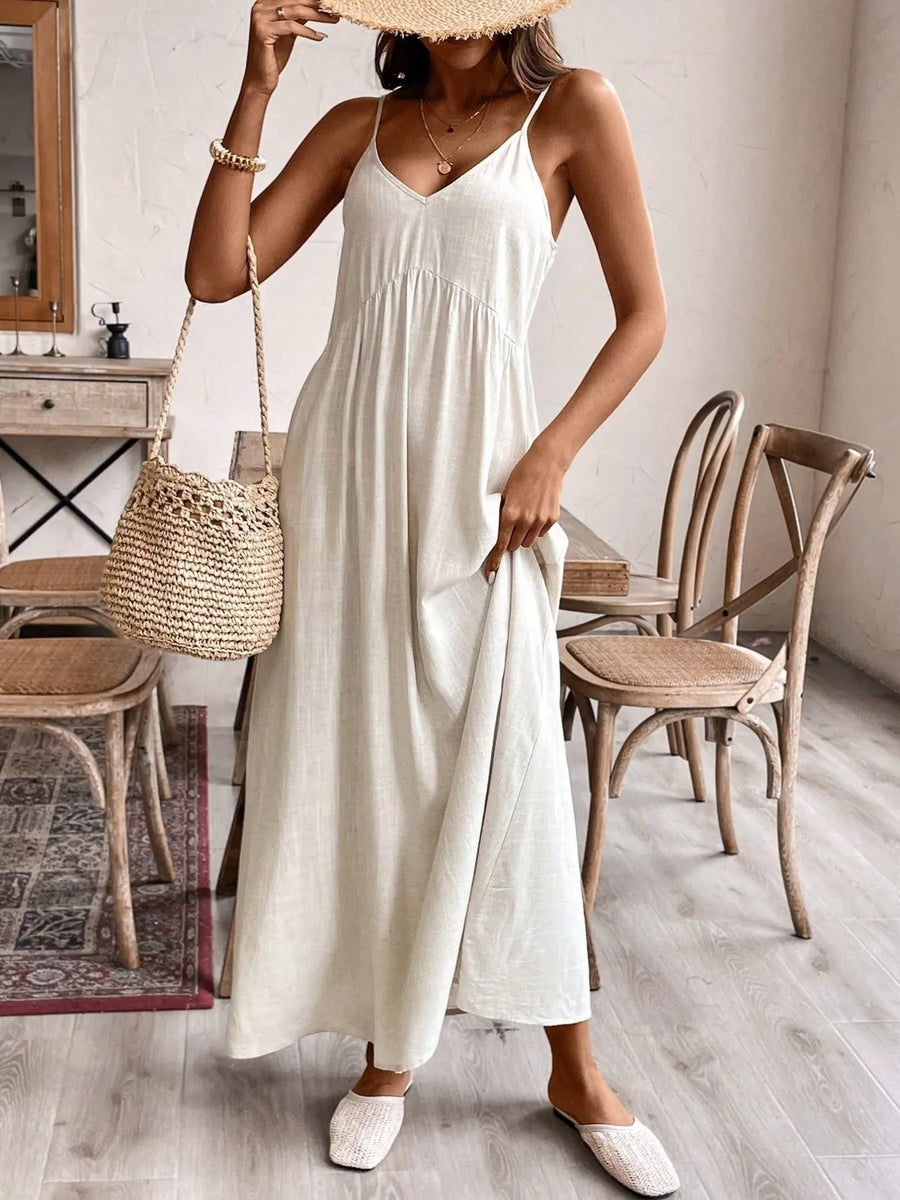 Woman in a white dress holding a straw bag in a room with wooden furniture.