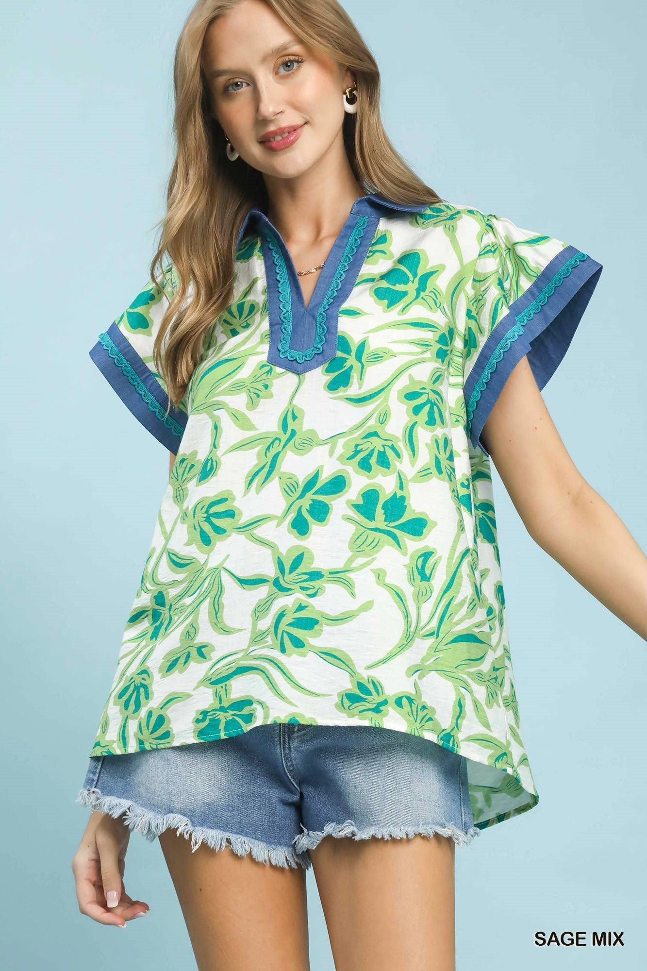 Woman wearing a green floral blouse with blue accents on a light blue background