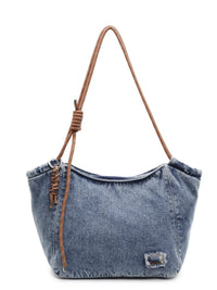 Denim handbag with brown leather strap on a white background