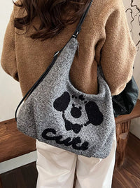 Person holding a gray tote bag with a black dog design and 'Cute' text.