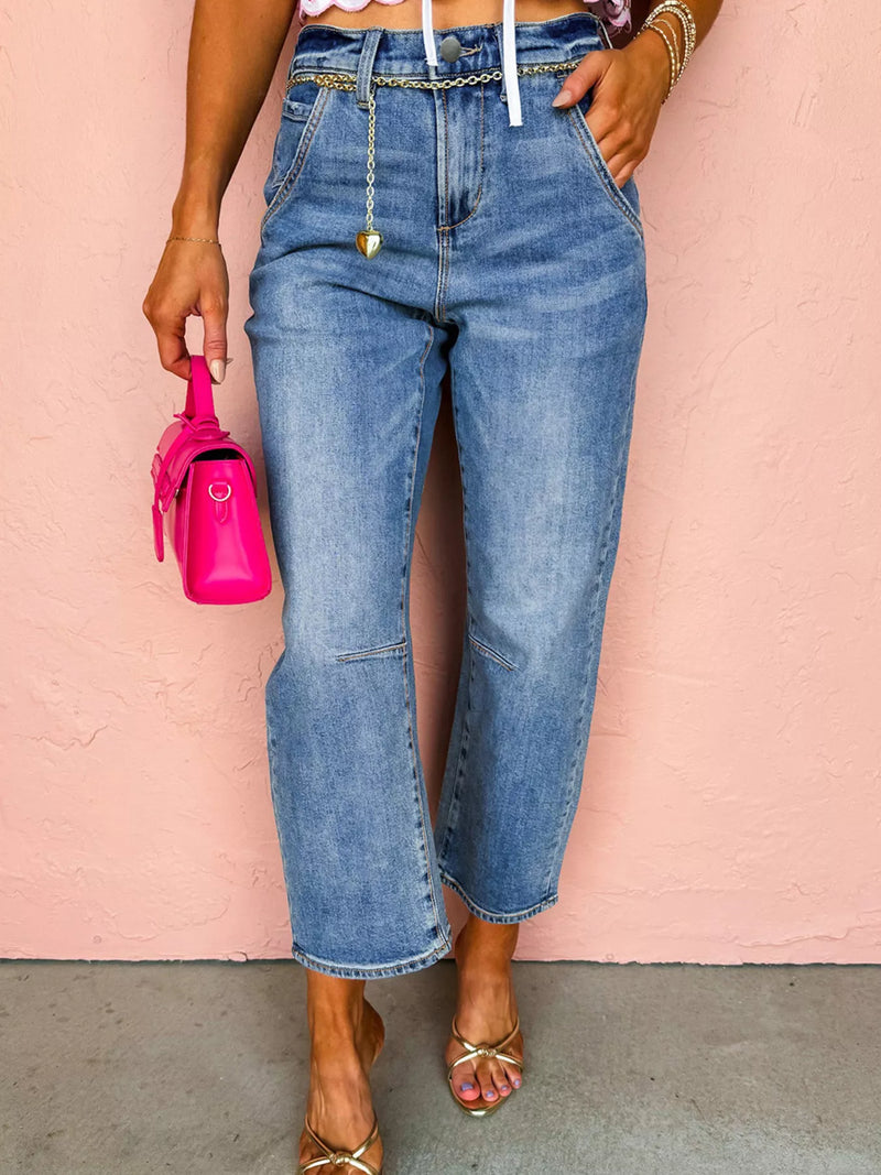 Person wearing high-waisted blue jeans with a pink background