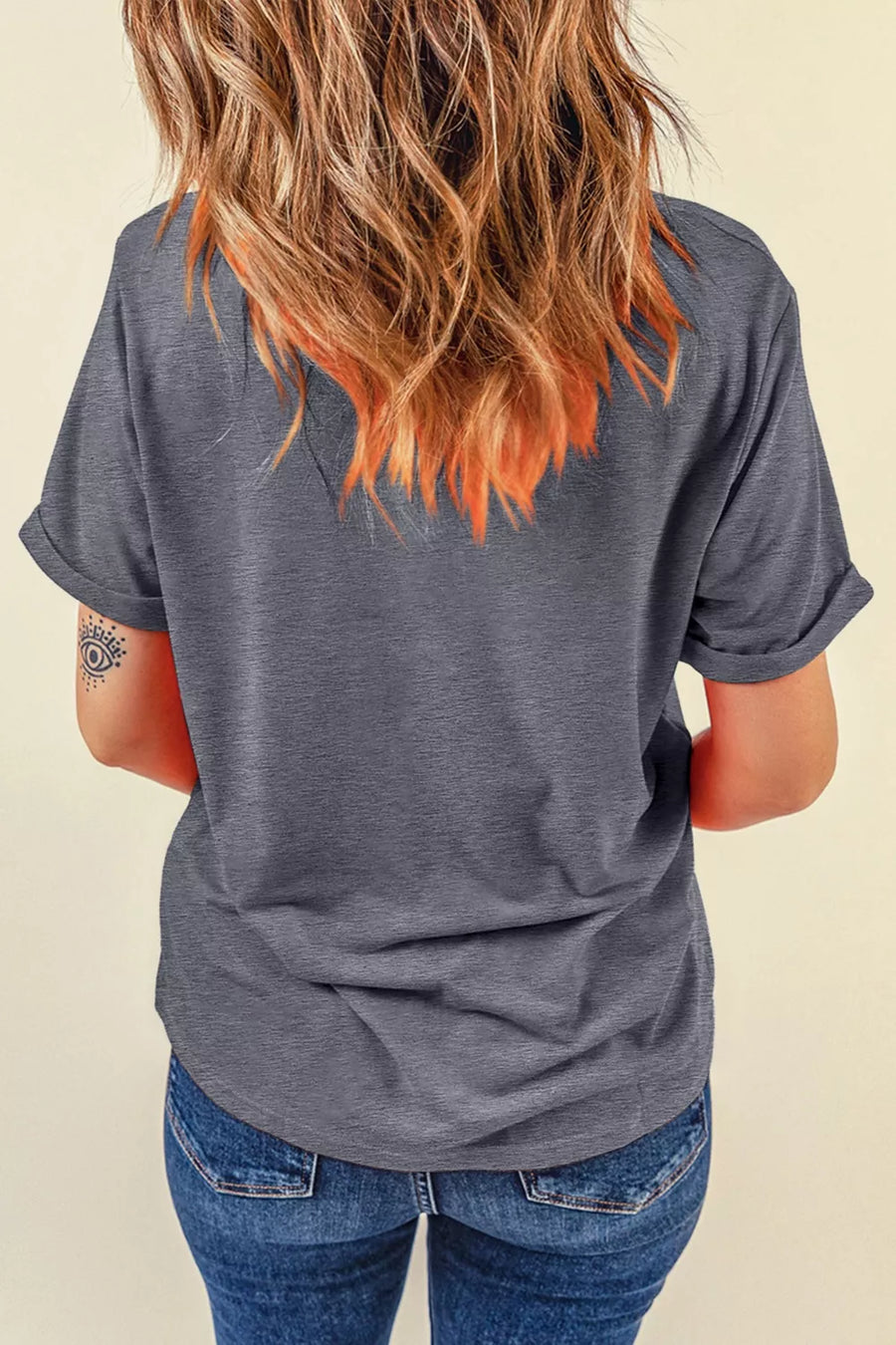 Person wearing a gray t-shirt and blue jeans with a neutral background