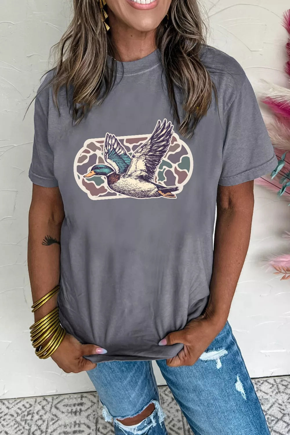 Woman wearing a gray t-shirt with a duck graphic design.