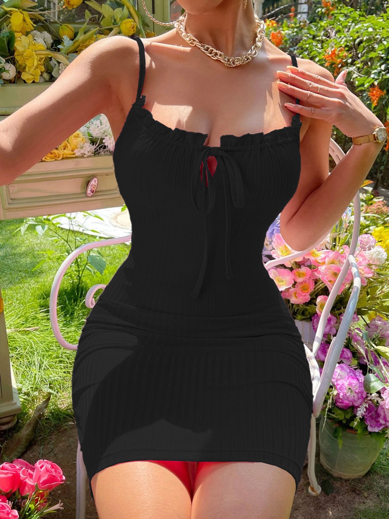 Woman wearing a black dress with red accents in a garden setting