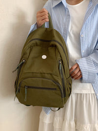 Person holding a green backpack against a neutral background