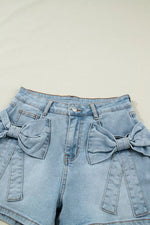 Light blue denim shorts with bow details on a beige background