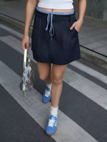 Person wearing a black skirt and blue sneakers on a city street.