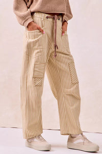 Person wearing beige striped pants and a matching top against a plain background