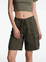 Person wearing olive green cargo shorts on a white background