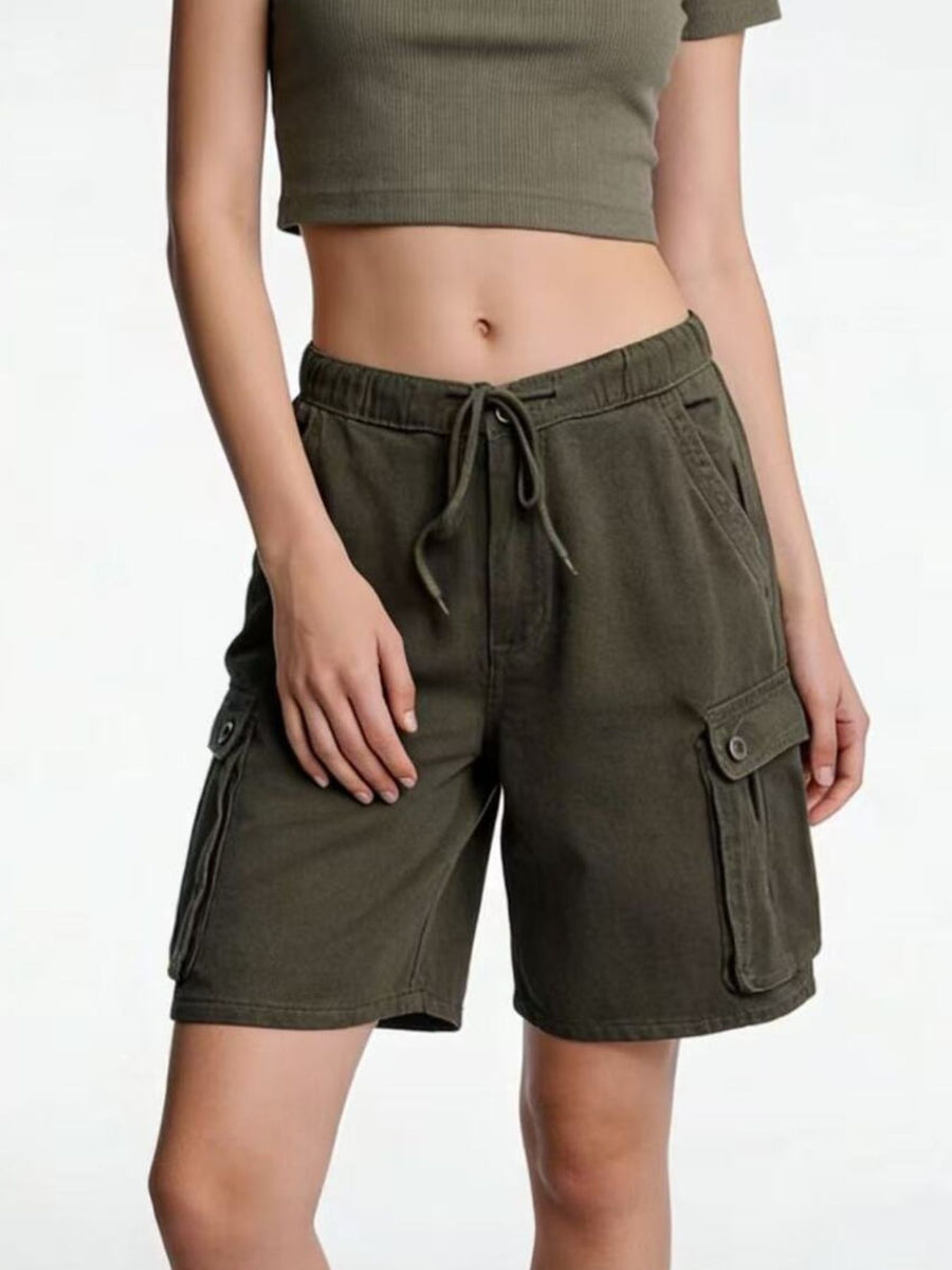 Person wearing olive green cargo shorts on a white background