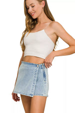 Woman wearing a white crop top and denim skirt on a white background
