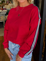Person wearing a red sweatshirt with white stripes on a blurred indoor background