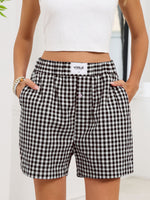 Person wearing black and white checkered shorts with a visible brand label on a light background