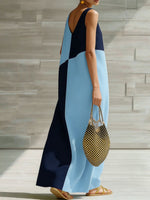 Woman wearing a blue and black dress holding a polka dot handbag on a wooden deck.