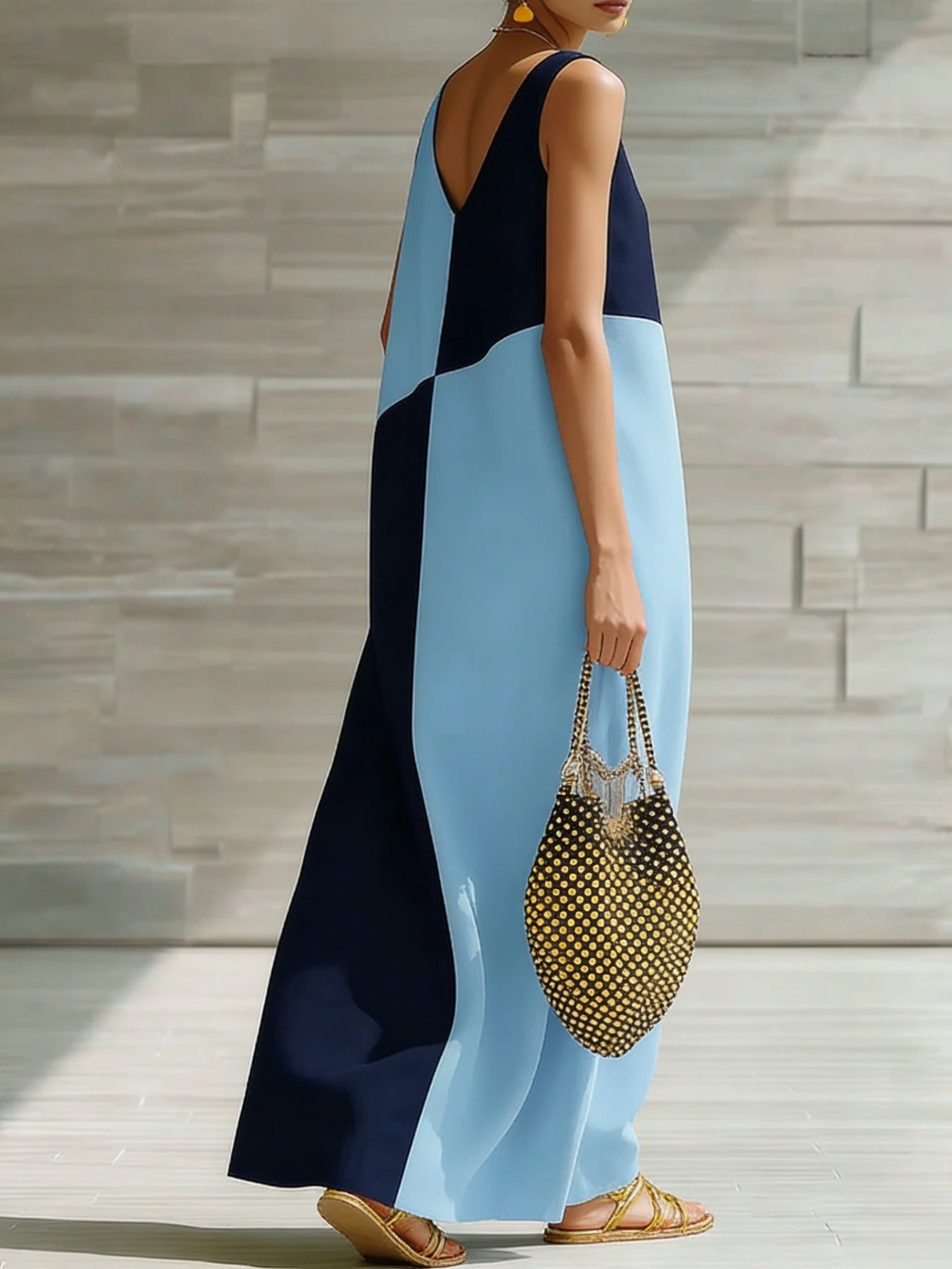Woman wearing a blue and black dress holding a polka dot handbag on a wooden deck.