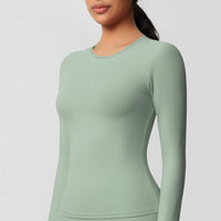 Person wearing a light green long-sleeve top on a plain background