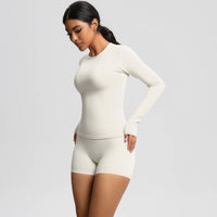 Woman wearing a white long-sleeve top and shorts set on a light gray background