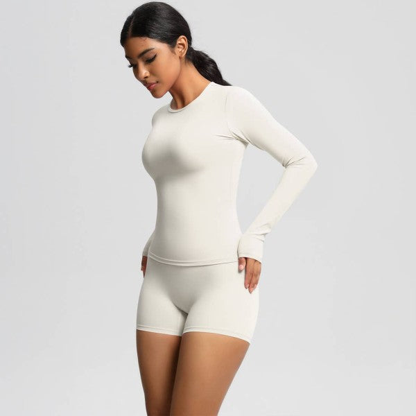 Woman wearing a white long-sleeve top and shorts set on a light gray background