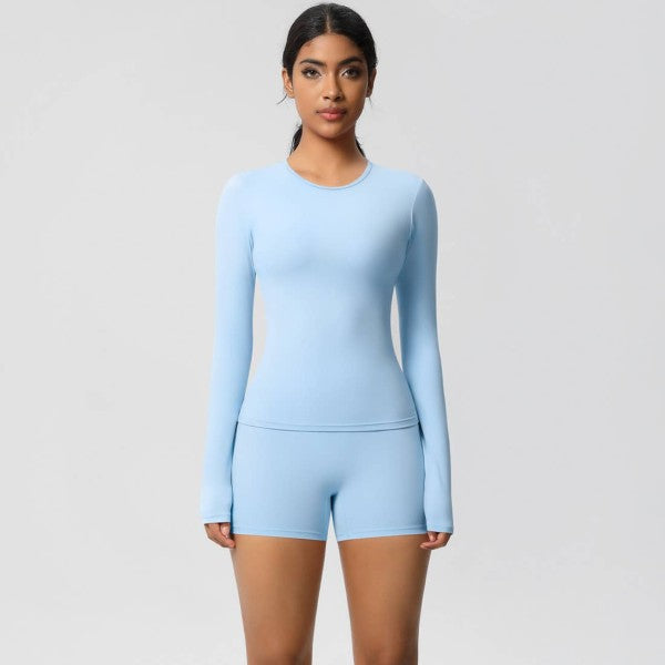 Woman wearing a light blue long-sleeve top and shorts set on a plain background