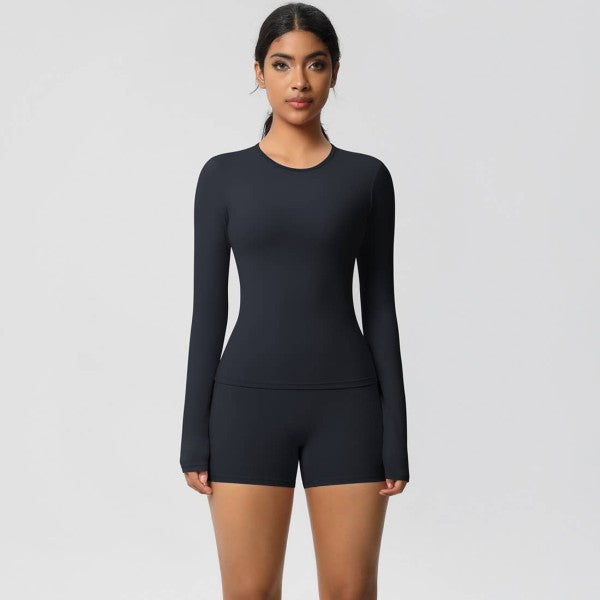 Woman wearing a black long-sleeve top and shorts on a light gray background