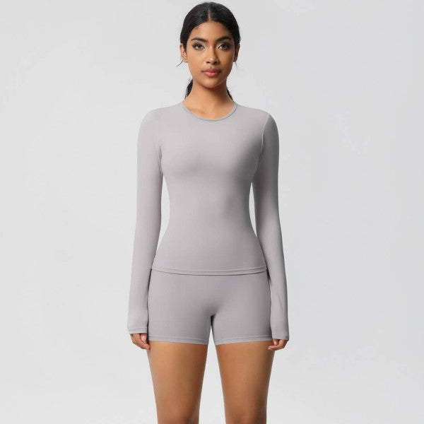 Woman wearing a gray long-sleeve top and shorts set on a light gray background