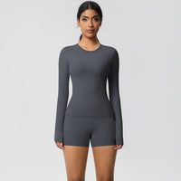 Woman wearing a gray long-sleeve top and shorts on a light gray background