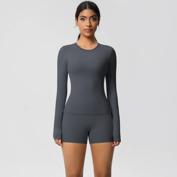 Woman wearing a gray long-sleeve top and shorts on a light gray background