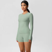 Woman wearing a green long-sleeve romper on a light gray background