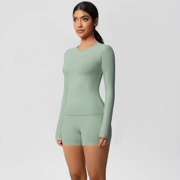 Woman wearing a green long-sleeve romper on a light gray background