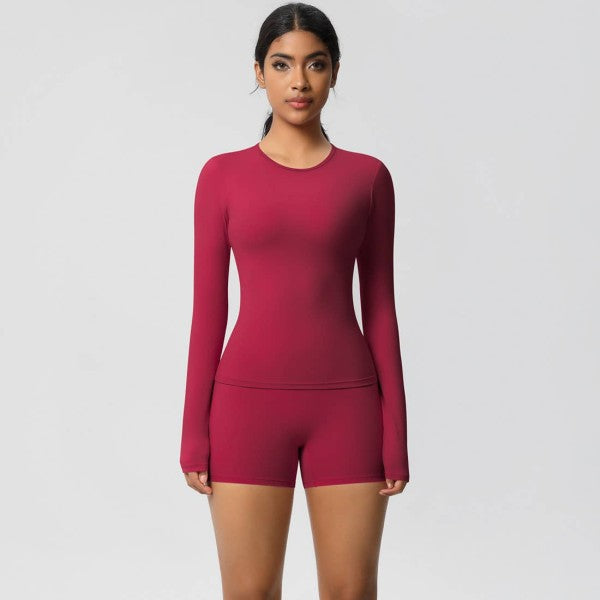 Woman wearing a pink long-sleeve top and shorts set on a light gray background