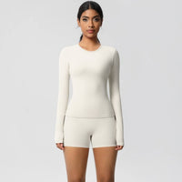 Woman wearing a white long-sleeve top and shorts set on a light gray background