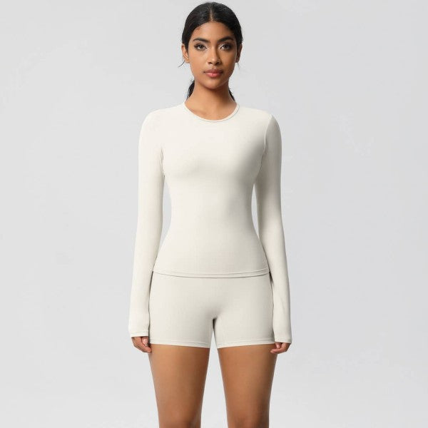 Woman wearing a white long-sleeve top and shorts set on a light gray background