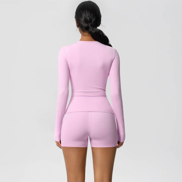Person wearing a pink long-sleeve romper on a light gray background