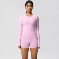 Woman wearing a pink long-sleeve top and shorts set on a light gray background