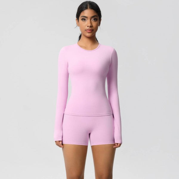 Woman wearing a pink long-sleeve top and shorts set on a light gray background