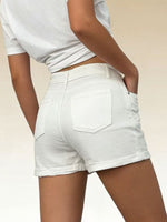 Person wearing white denim shorts on a plain background