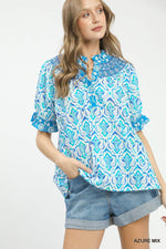 Woman wearing a blue and white patterned blouse with denim shorts on a white background
