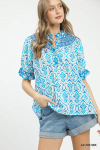 Woman wearing a blue and white patterned blouse with denim shorts on a white background