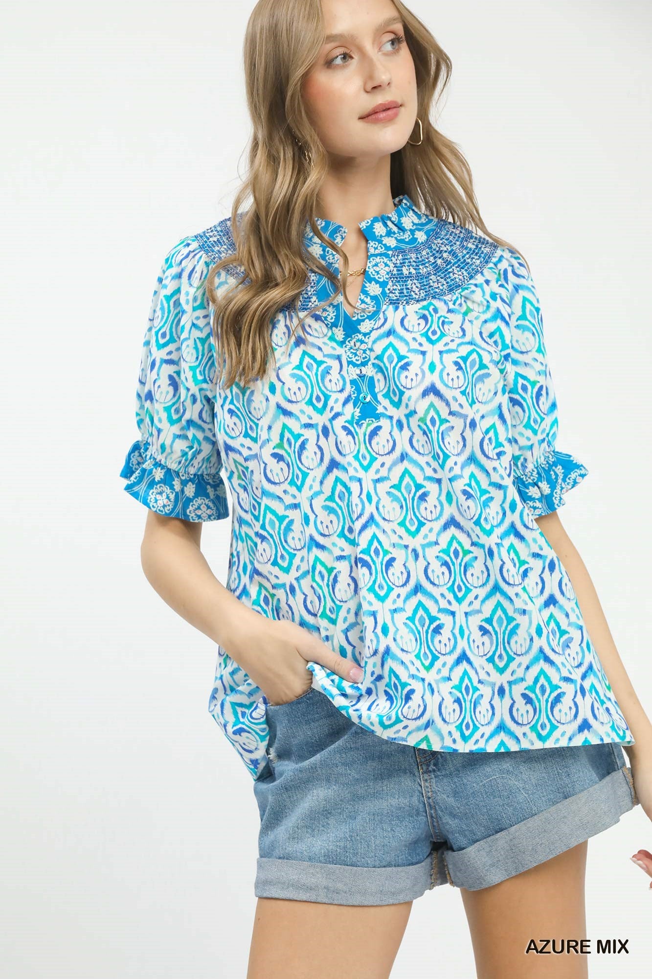 Woman wearing a blue and white patterned blouse with denim shorts on a white background
