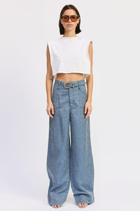 Woman wearing a white sleeveless top and blue wide-leg jeans on a white background