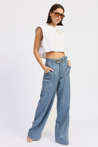 Woman wearing a white sleeveless top and blue jeans on a white background