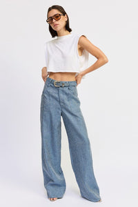 Woman wearing a white sleeveless top and blue jeans on a white background