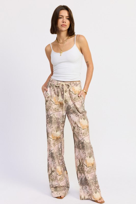 Woman wearing a white tank top and shell-patterned pants on a white background
