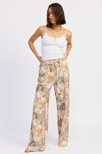Woman wearing a white tank top and patterned pants on a white background