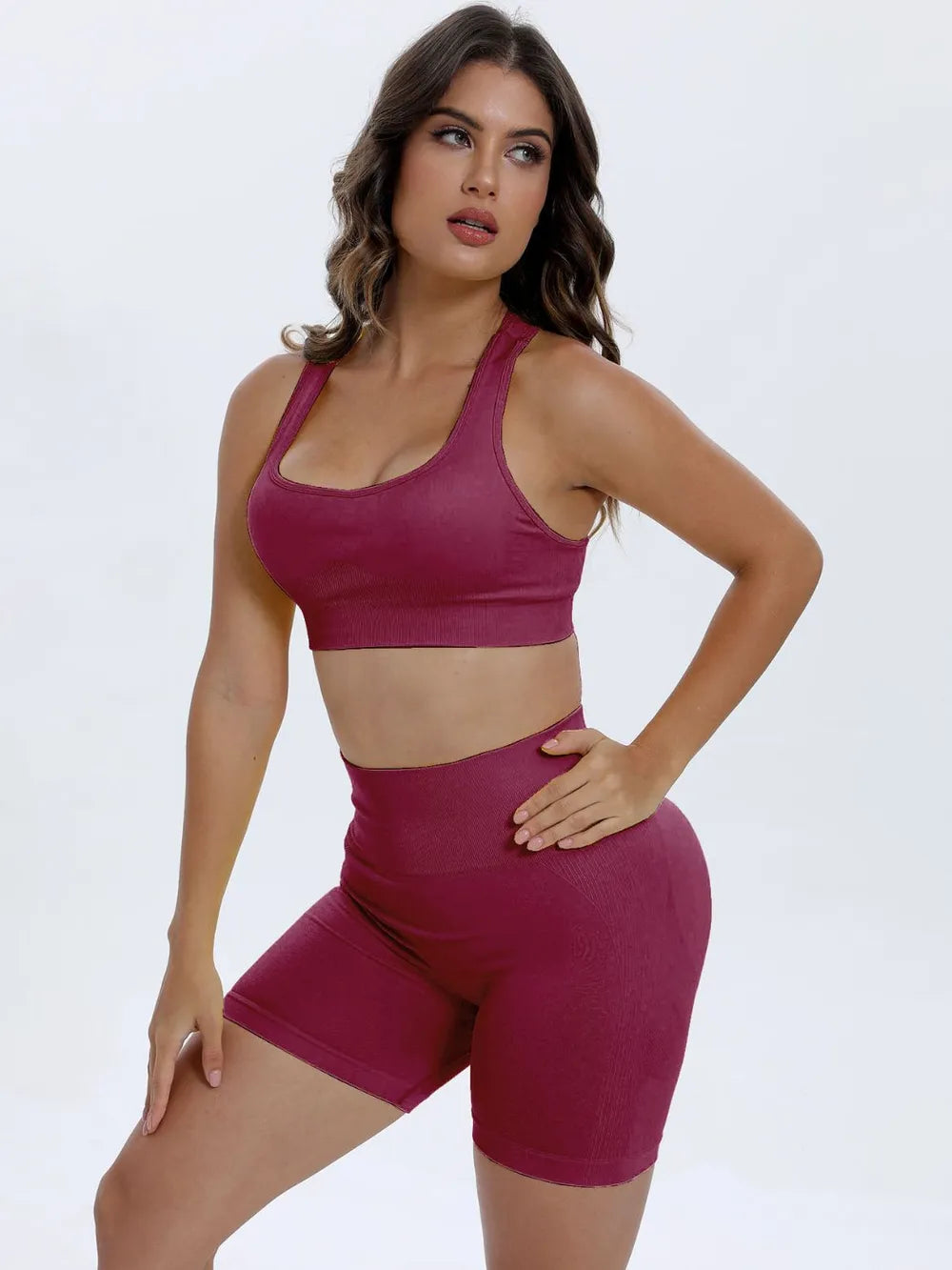 Woman wearing a maroon sports bra and shorts set on a white background