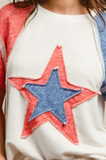 Close-up of a white sweater with red and blue star patches.